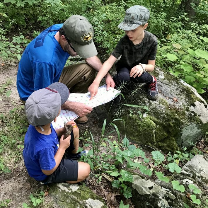 Outdoor classroom activity with children discovering native flowers and plants in nature.