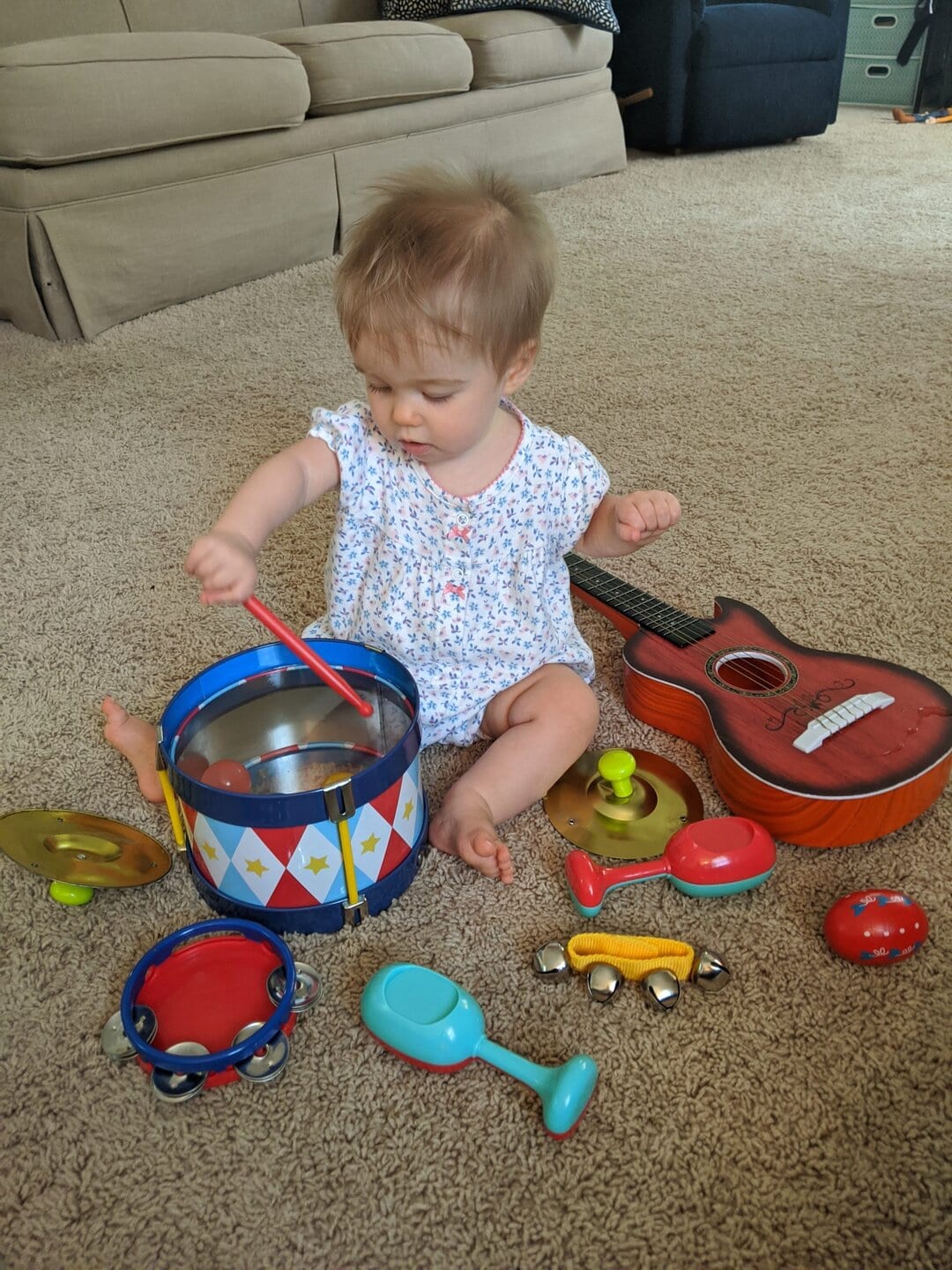 Child playing with musical toys and a guitar on the carpet.