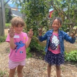 Two smiling children playing in a garden at miriam p. Brenner children's museum.