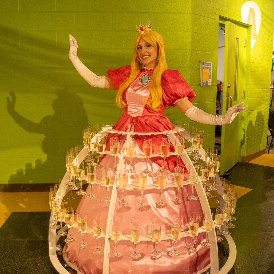 Woman dressed as a princess in a pink gown and crown at the museum.